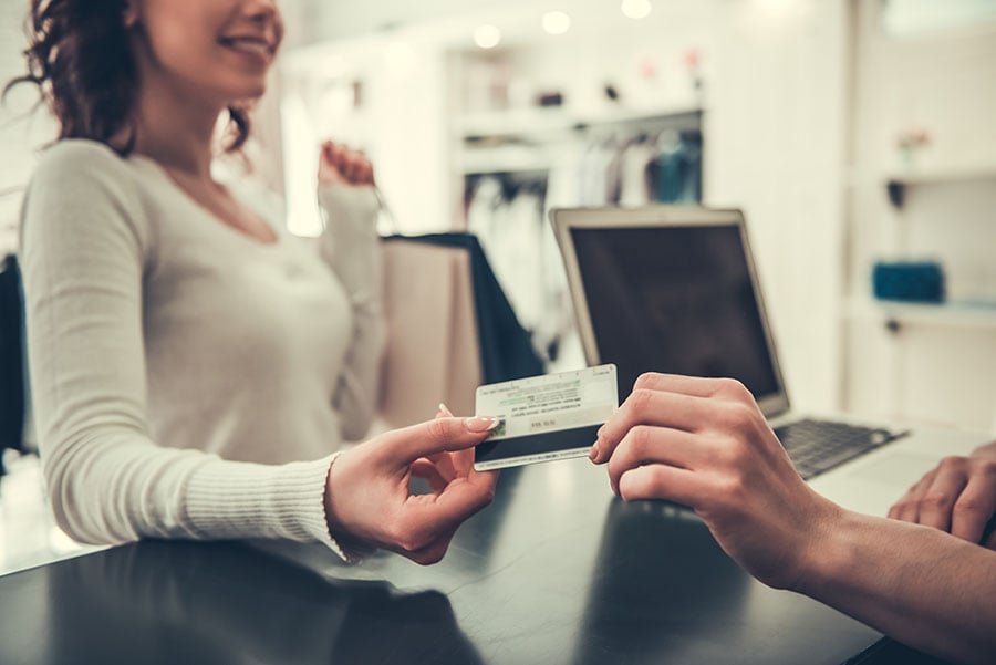 a woman chooses a credit union credit card vs. a bank credit card for making purchases during a shopping trip